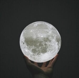 Main gauche tenant une lune du bout des doigts. Illustrant l'énergie, élément naturel, magnétisme